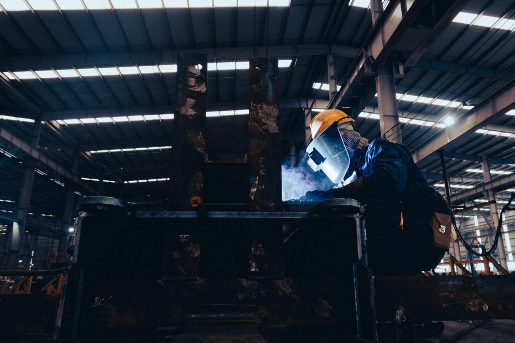 pexels-photo-17572739-17572739 A welder wearing protective gear works on metal in a dimly lit industrial workshop.