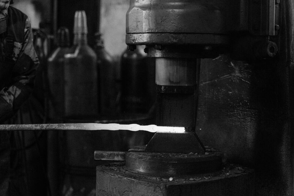 pexels-photo-5845944-5845944 Monochrome image of a blacksmith's forge with metal being processed.