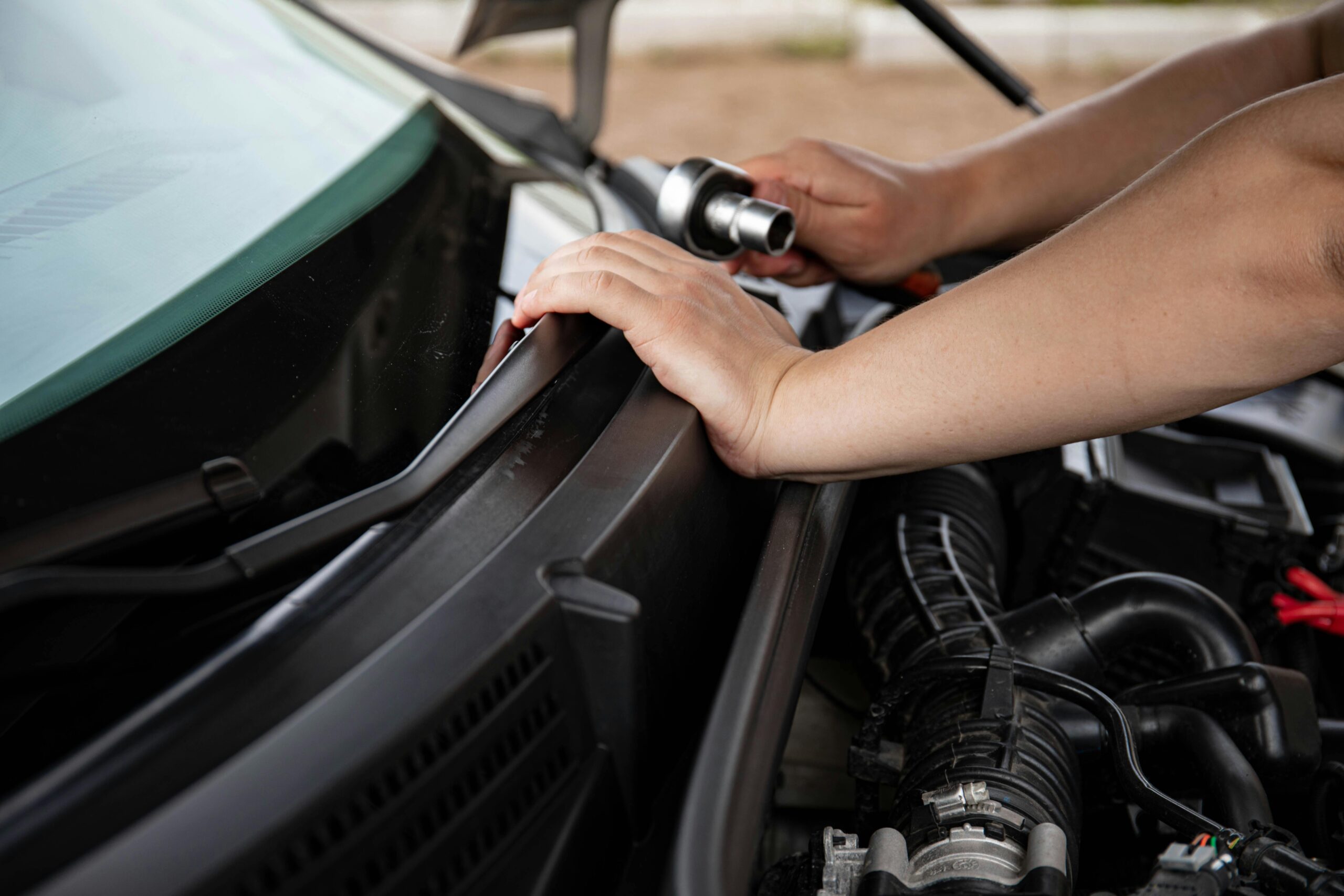 Close-up of a person repairing a car engine with a socket wrench.